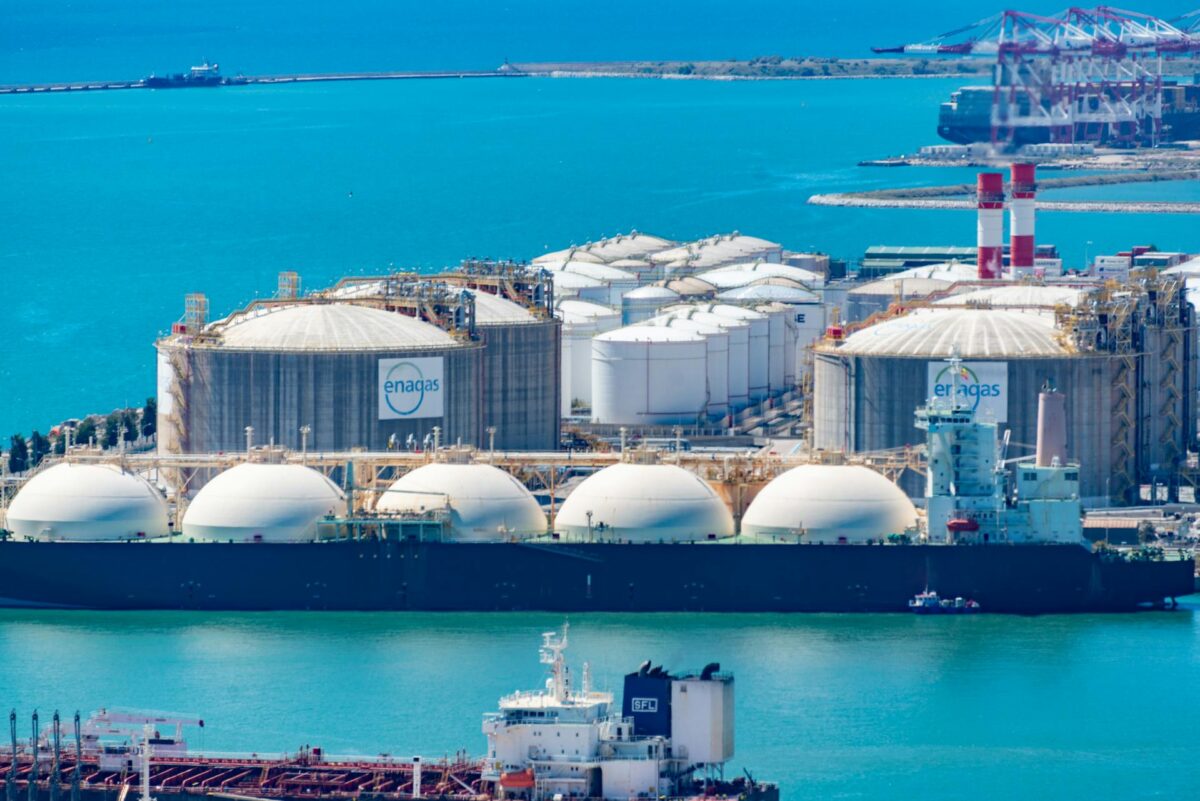 Gas terminal with LNG tanker and storage tanks as US natural gas markets face high inventories and weak Henry Hub prices.