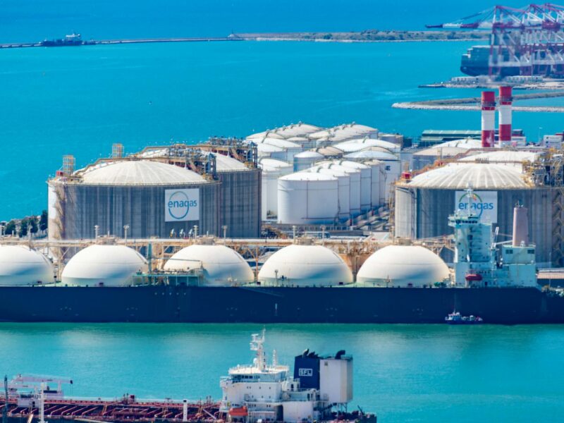 Gas terminal with LNG tanker and storage tanks as US natural gas markets face high inventories and weak Henry Hub prices.